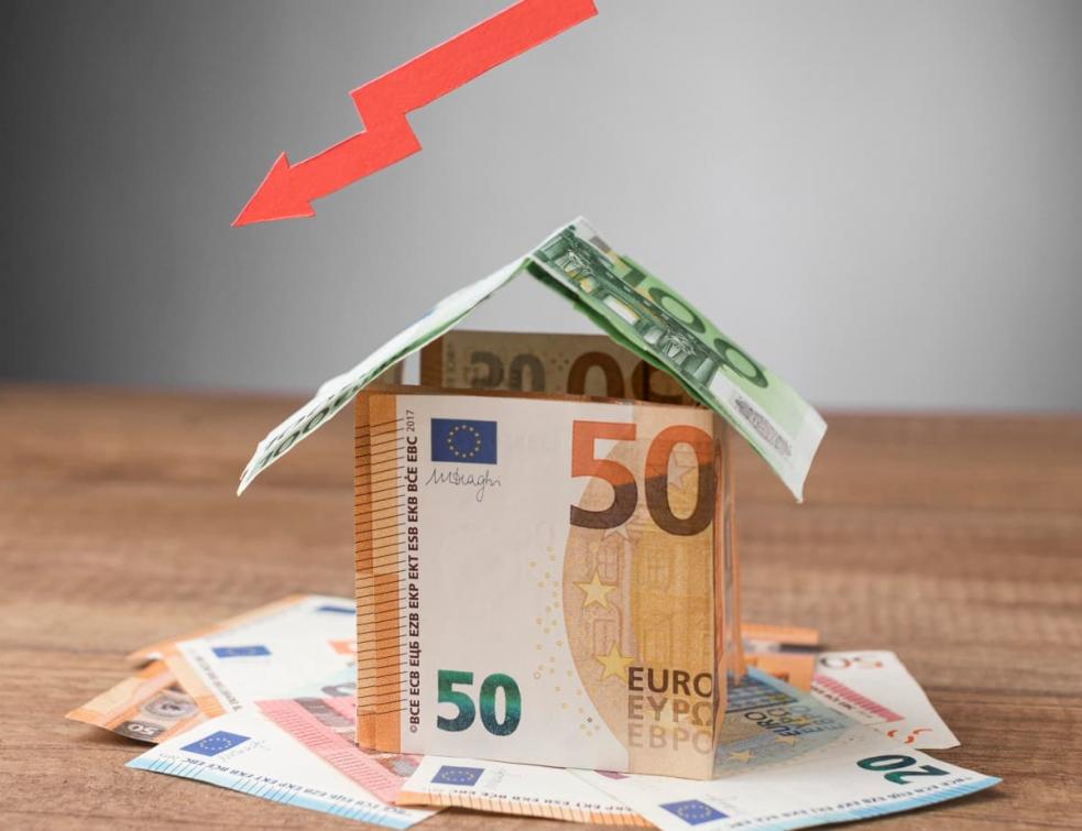 maison fabriquée avec des billets de 50 et 100 euros, fleche rouge pointant vers le bas.