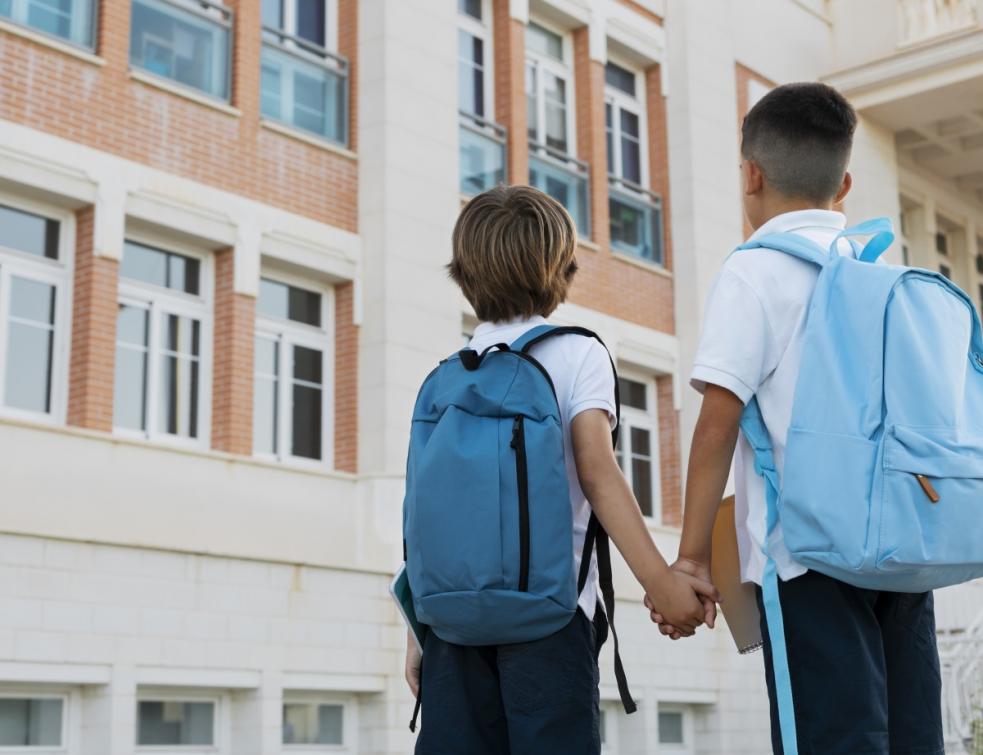 deux enfants se tiennent la main devant une école