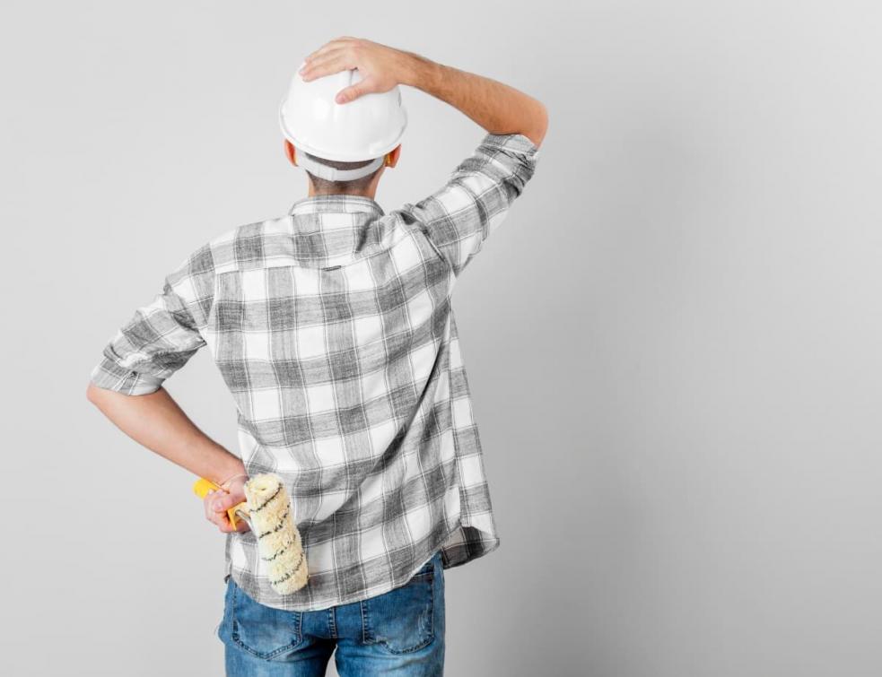 Homme portant un casque en questionnement devant un mur blanc