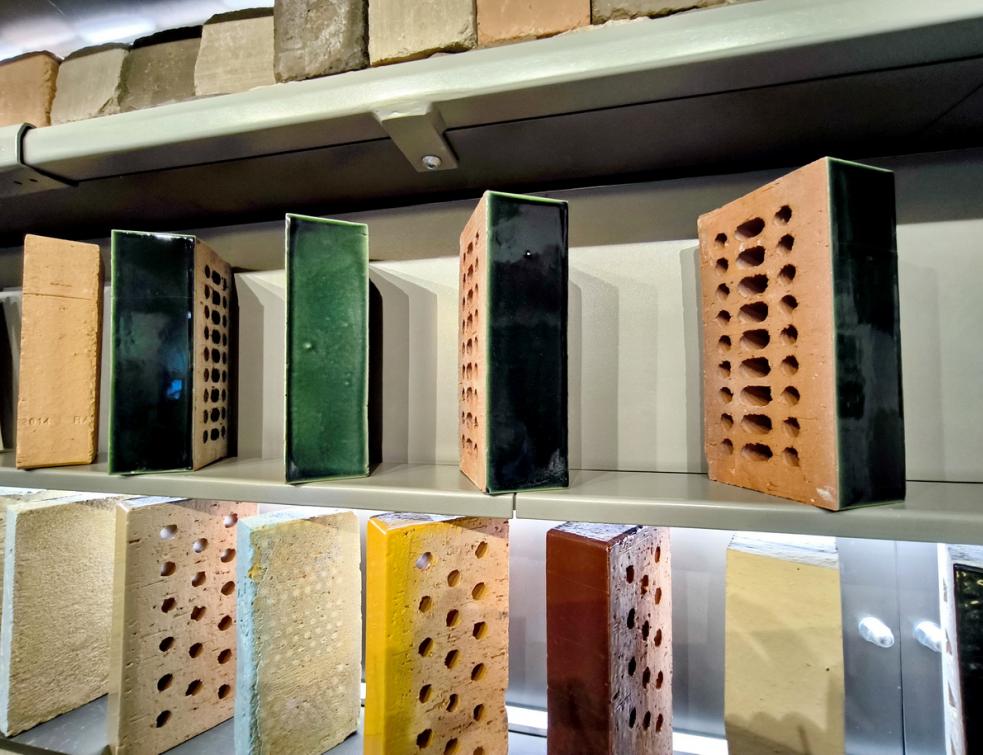 Des échantillons de briques de terre cuite Rairies Montrieux sur trois étagères dans leur showroom parisien. © PP