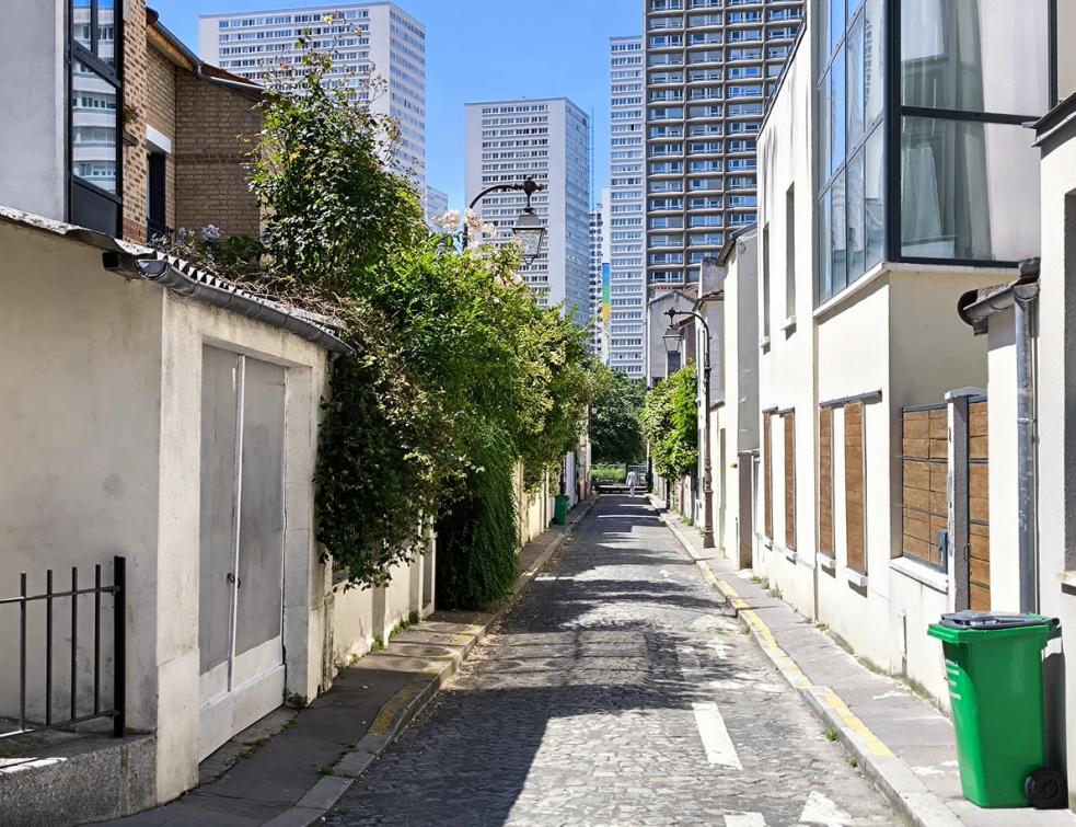 Une petite rue du treizième arrondissement de Paris bordée de maisons avec les tours de la Porte d'Ivry en perspective