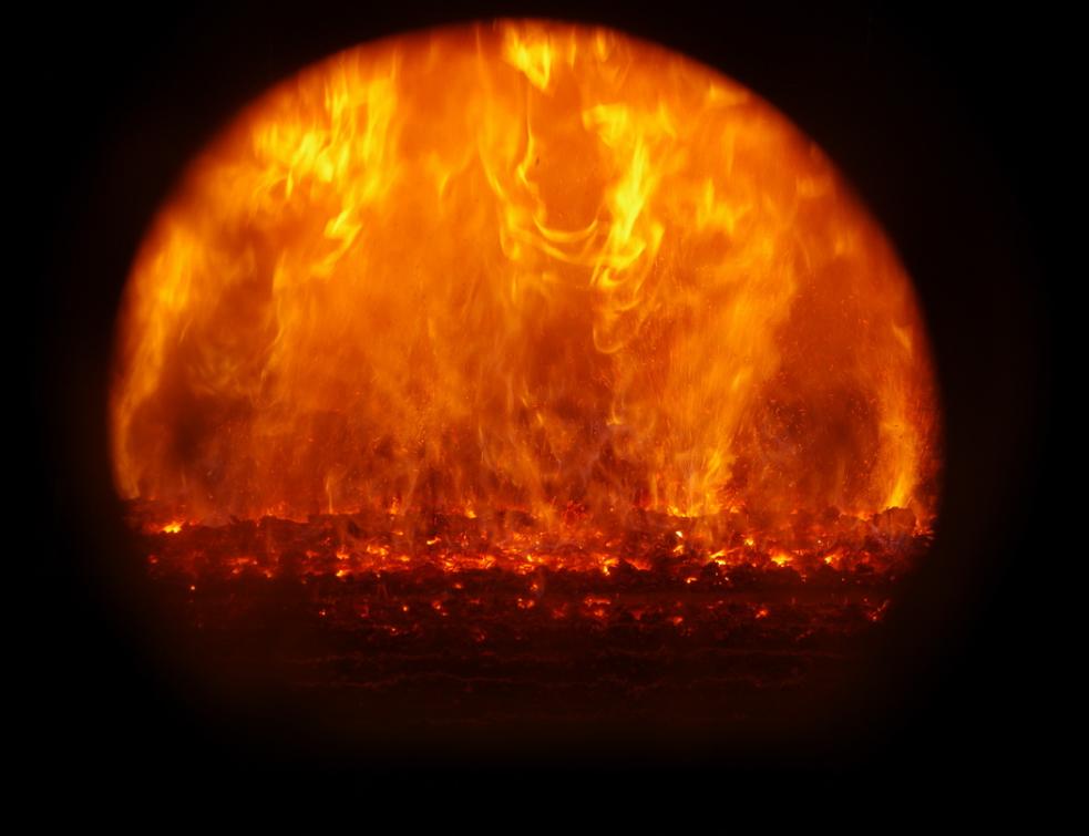 La flamme de la combustion du bois à travers la vitre d'un poêle à bois. ©